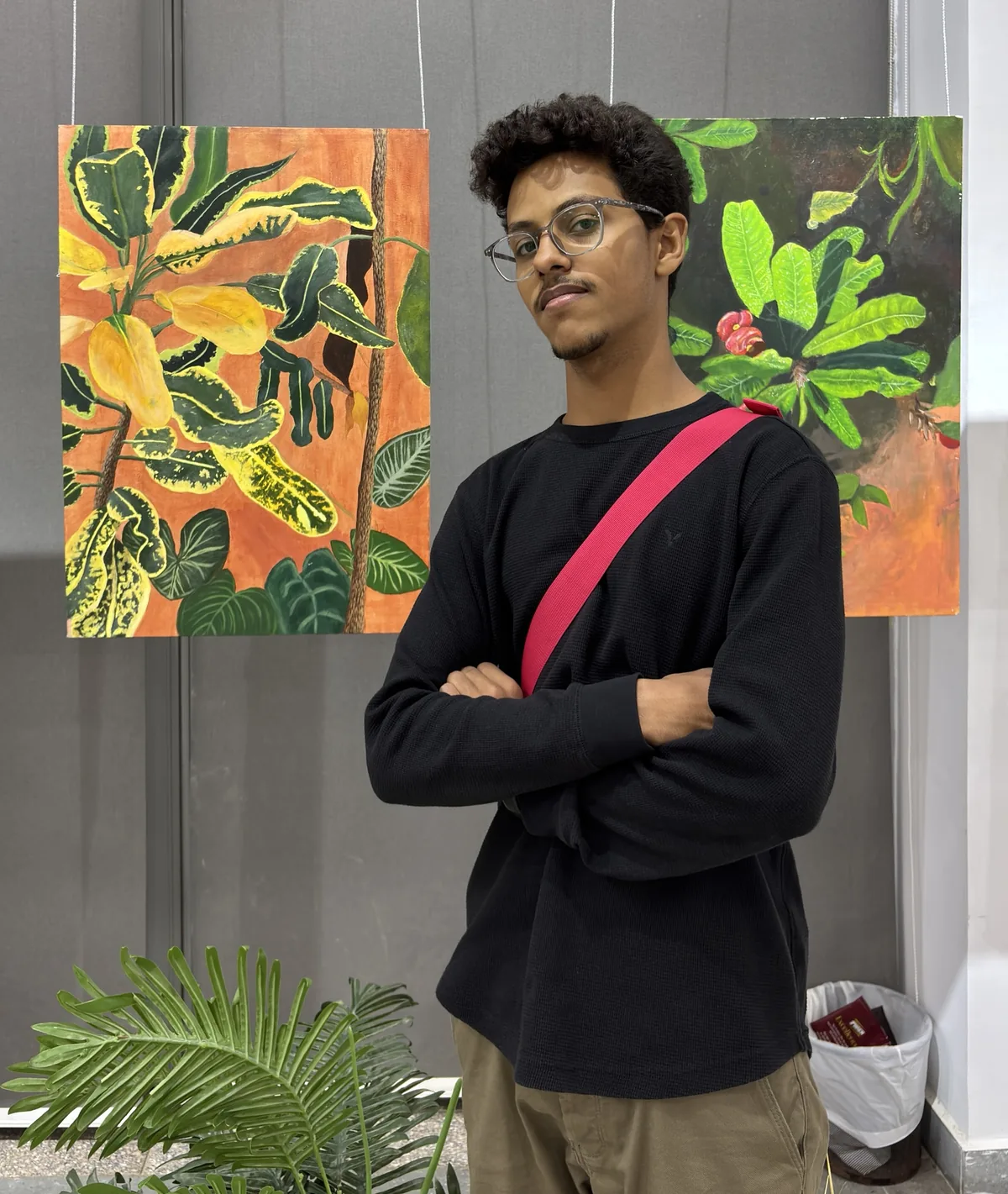 Feras Mamdouh at an exhibition of his paintings, arms crossed