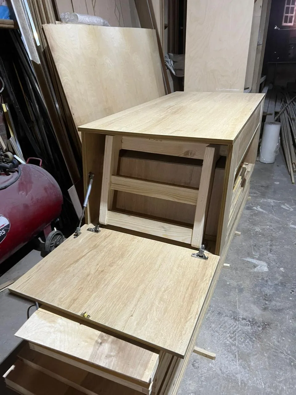 The built table with its front panel open and the chair frame stored inside