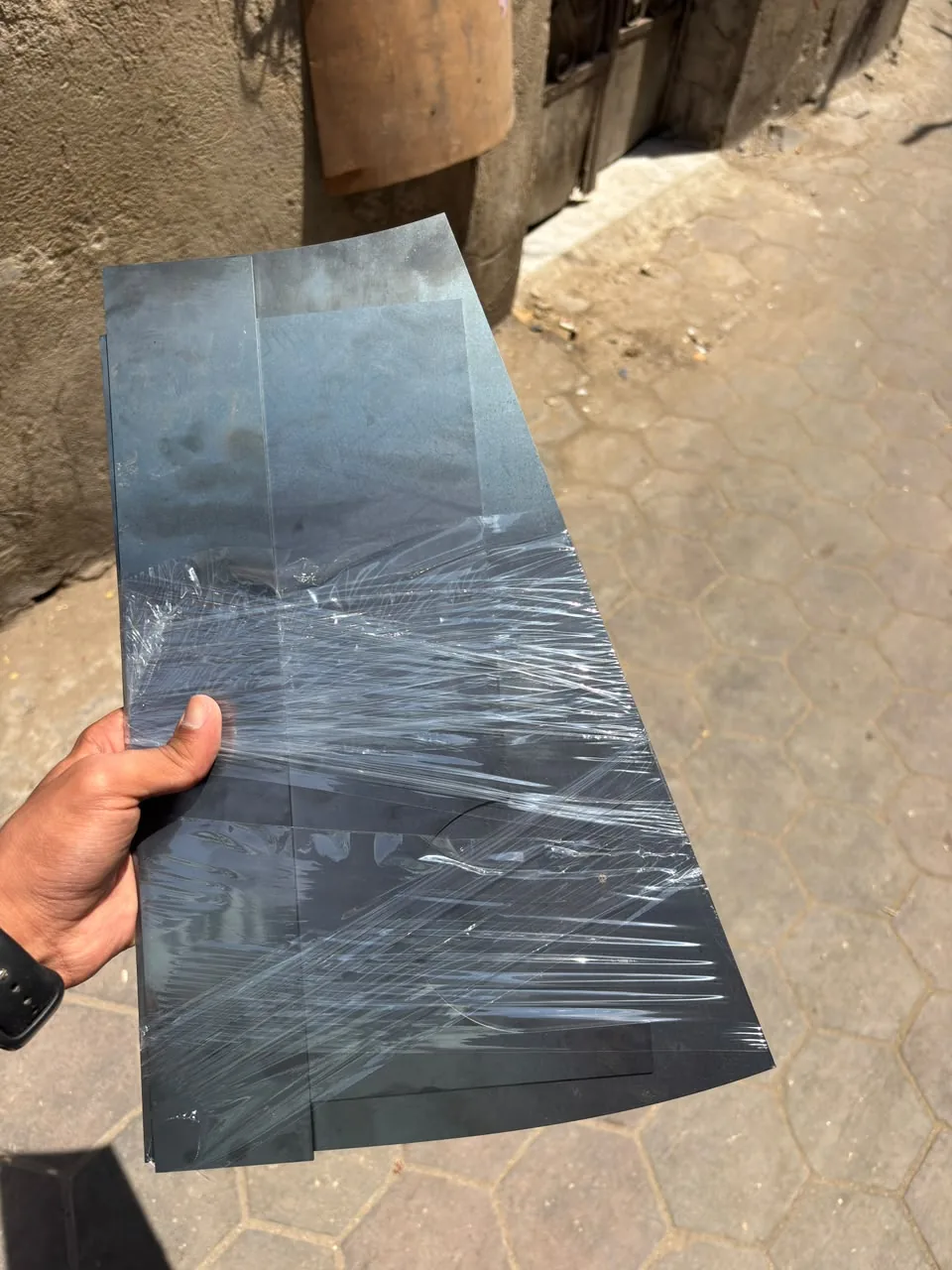 Laser-cut steel parts wrapped in plastic, held in a hand