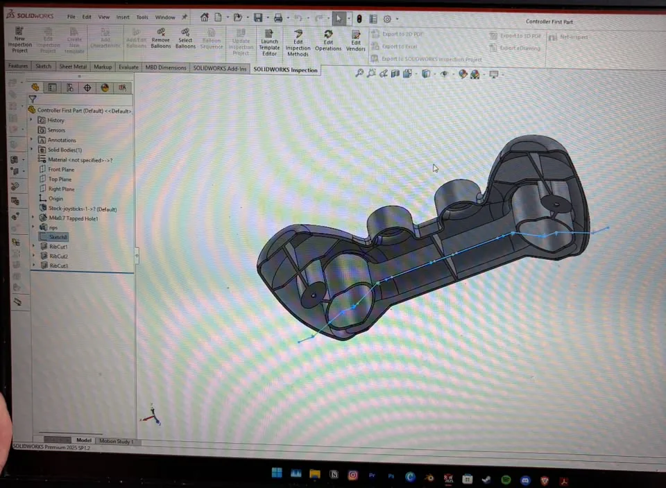 Laptop screen showing the controller body being modeled in SolidWorks